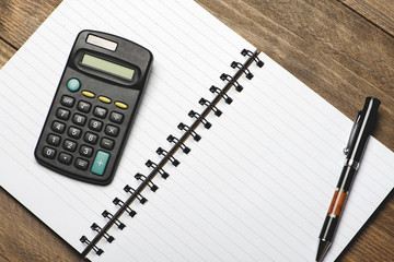 Office still-life with pen and calculator on brown wooden table.