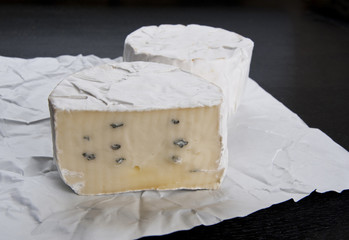 Soft cheese on white wrapping paper and black table