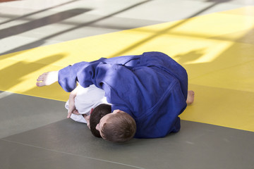 Two young judoka in kimono struggling on tatami