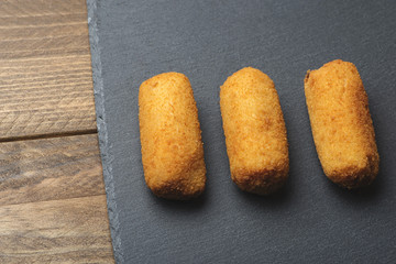 Close-up of several croquettes on slate plate. Horizontal shoot.
