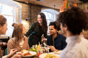 happy friends eating and drinking at restaurant