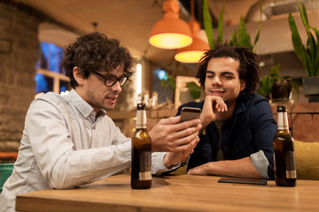 men with smartphones drinking beer at bar or pub