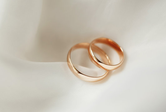  gold wedding rings lying on white satin