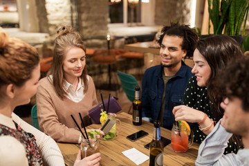 friends with drinks, credit card and bill at bar