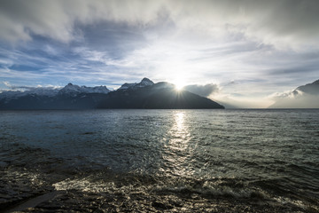 Evening. Landscape a mountain lake in the Alps. Switzerland. Sun rays over the mountain peaks.