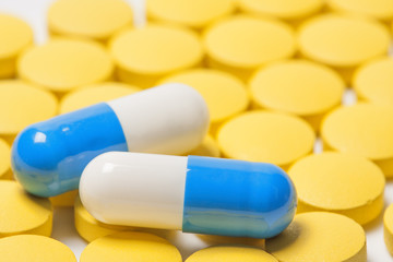 Two blue medical pills on yellow background