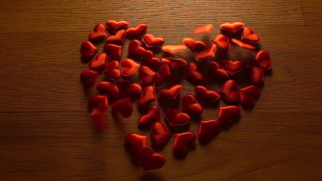 Small hearts combine big heart shape on wooden surface. Super slow motion video