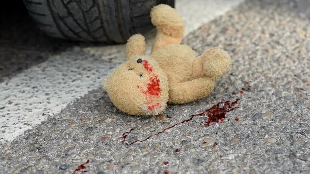 soft toy bear in the blood under the car wheels