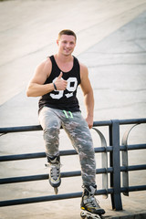 young fit man with inline skates rest in summer park after workout outdoor roller skater thumbs up