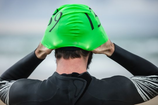 Athlete in wet suit wearing swim cap on the beach