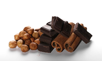 chocolate bars with cinnamon sticks and pile hazelnuts isolated on white background