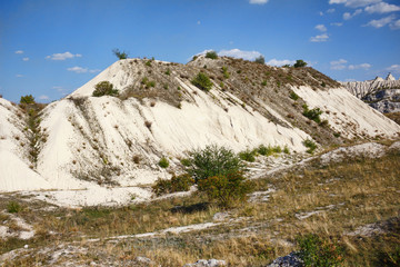 View on hills and fields from a limestone cliff at a quarry under a beautiful blue sky, abandoned white stone career, in fetesti village, Moldova