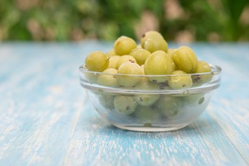 Frozen berries gooseberries in a bowl of glass on vintage table.