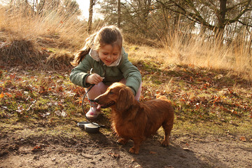 girl putting leash on a dachshund dog