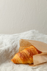 Delicious french freshly baked croissants in paper bag on a textile background.