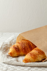 Delicious french freshly baked croissants in paper bag on a textile background.