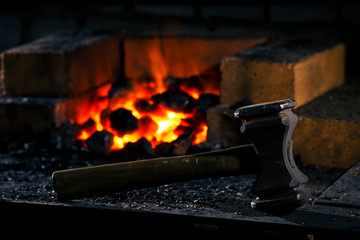 Blacksmith hammer on the anvil against the background of fire.