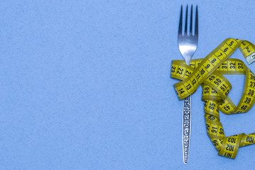 Measuring tape on a fork - dieting concept image