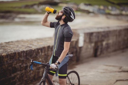 Athlete refreshing from bottle while riding a bicycle 