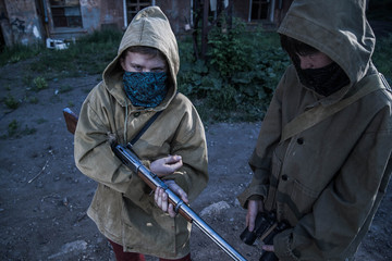 young militiaman. Two young boys standing in front of an abandoned building. a boy with a gun. Teen...