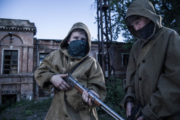 young militiaman. Two young boys standing in front of an abandoned building. a boy with a gun. Teen...
