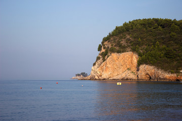 Fototapeta na wymiar Rock with trees on the background of sea and blue sky
