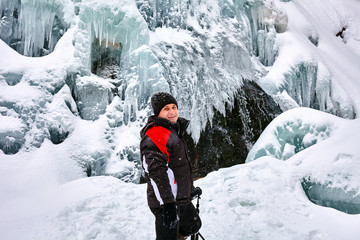 Fototapeta na wymiar Landscape photographer at frozen waterfall