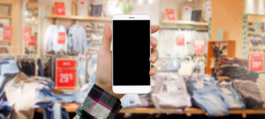 Women holding smartphone in shopping mall, buying clothes online. Empty screen for adding interface. Vertical smartphone view.


