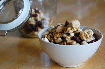 white ceramic bowl full of walnuts, cashew nuts and dried cranberries  