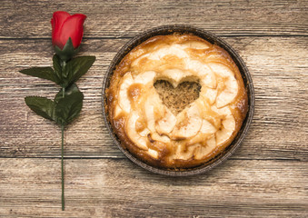 Apple pie with a hollow in the shape of a heart on a wooden tabl