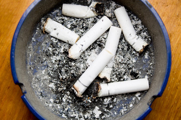 ashtray with cigarette butts on wooden