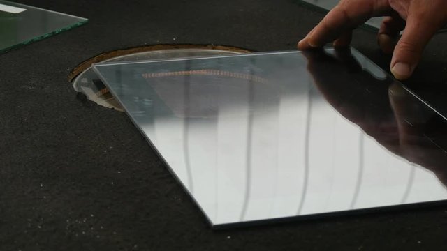 Closeup Shot of a Sheet of a Bulletproof Glass Moved Over Some Round Glass Testing Device by the Hands of Some Specialist in Its Producing in a Laboratory of Glass Control