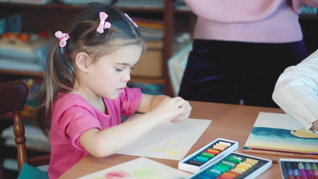 Girl draws with crayons at the table