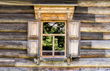 Window of old log house with carved wooden trim