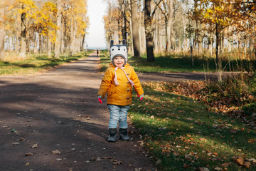 Baby girl walking smiling in the autumn park