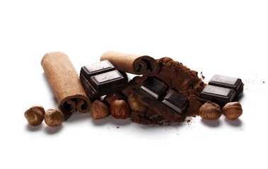 chocolate bars, cocoa powder with cinnamon sticks and pile hazelnuts isolated on white background