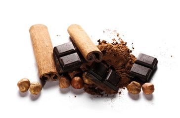 chocolate bars, cocoa powder with cinnamon sticks and pile hazelnuts isolated on white background