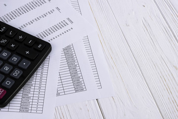 calculator and financial paper on white wooden table