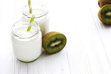 Fresh homemade yogurt with  kiwi fruit and straw on white backgr
