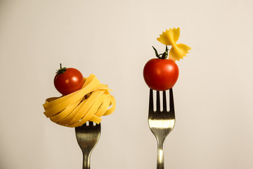 tagliatelle and butterfly pasta with tomatoes on forks