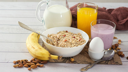 Healthy breakfast with muesli, egg, juice, yogurt, nuts and banana