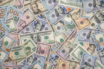 Stack of US dollars in cash in wooden desk.