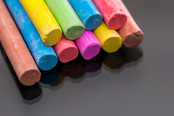 Multi colored chalk isolated on black background .