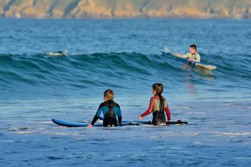 Deux enfants avancent dans l'eau pour pratiquer le surf