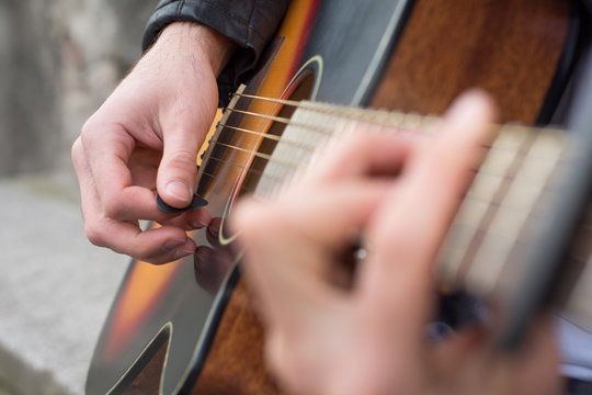 Acoustic guitar close-up with fingers playing it