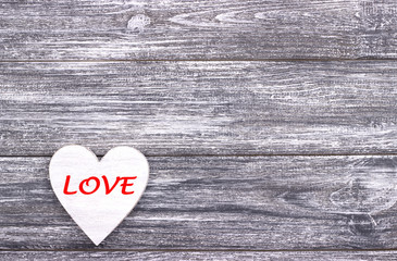 Decorative white heart on grey wooden background with copy space.