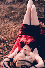 Beautiful and elegant blonde woman with red lips and hair waves wearing wine red nightie posing on...