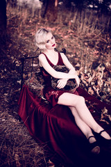 Beautiful and elegant blonde woman with red lips and hair waves wearing wine red nightie posing on...