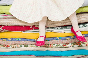 Legs of a little girl sitting on a pile of colorful mattresses. Decorations for the fairy tale The princess on a Pea © goodmoments