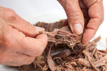 Closeup of woman hands shredding beef